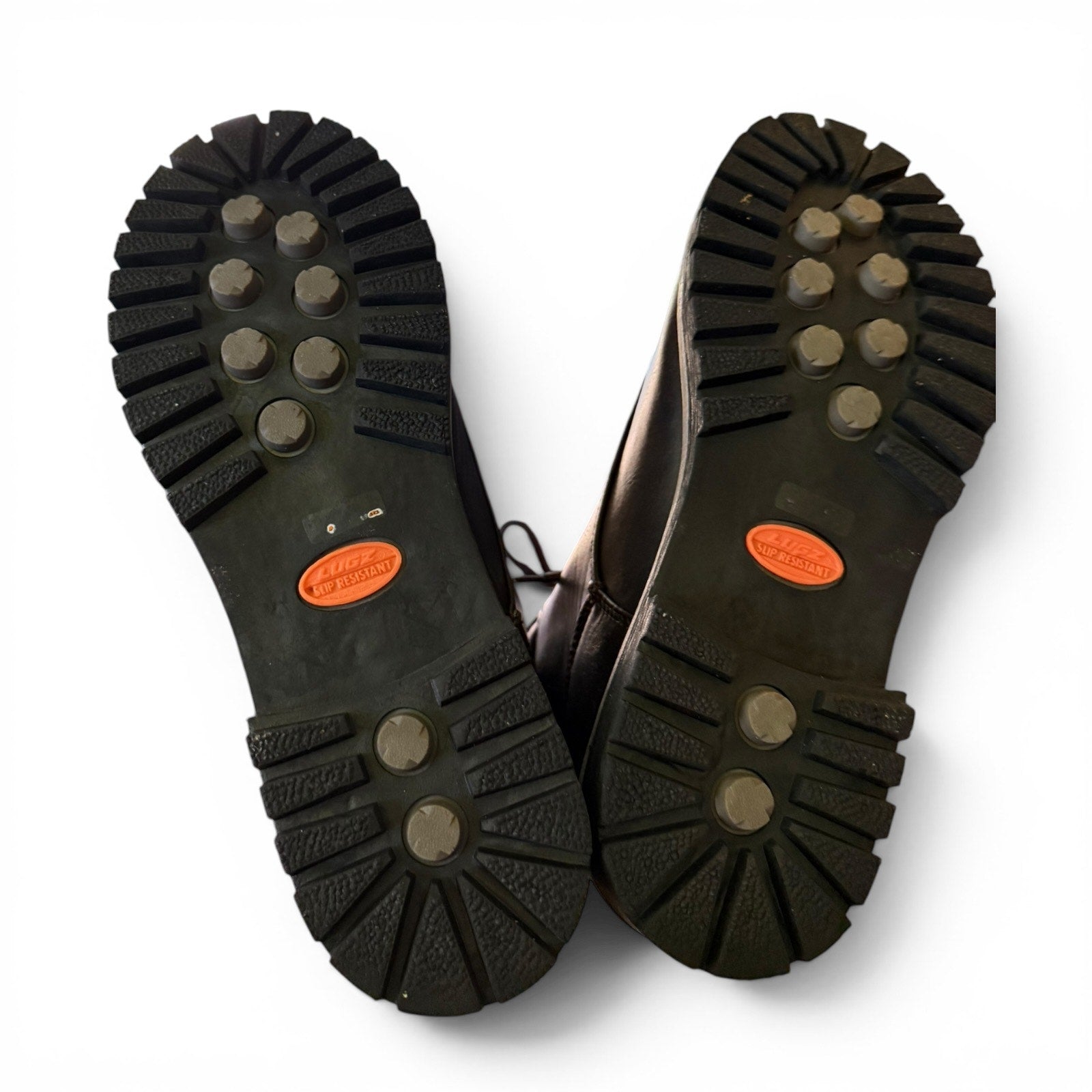 Bottom of shoes that are black with orange labels on a white background