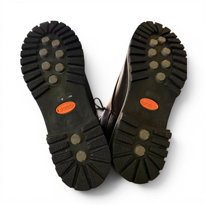 Bottom of shoes that are black with orange labels on a white background