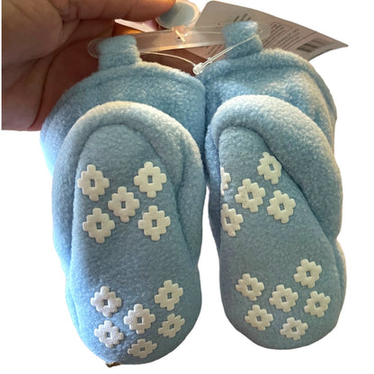 Pair of blue baby shoes with white floral patterns held by a hand against a white background.