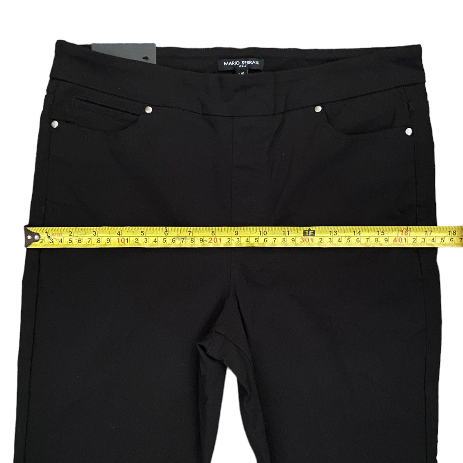 Black pants with a measuring tape across them on a white background