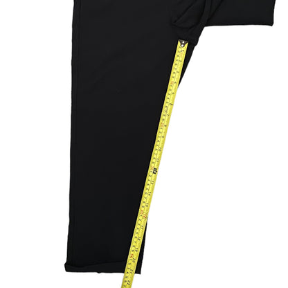 Black pants  with a yellow measuring tape draped over it on a white background