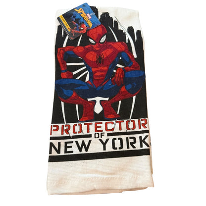 A folded white  towel featuring a large graphic of Spider-Man crouching above the text 'PROTECTOR OF NEW YORK' in red and black. A Spider-Man themed paper tag is attached at the top.