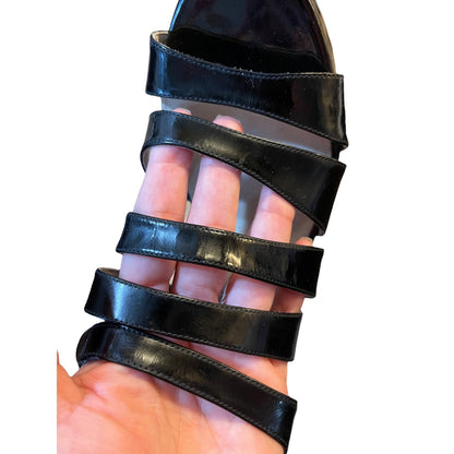 Black sandal with multiple straps being held up to a white background