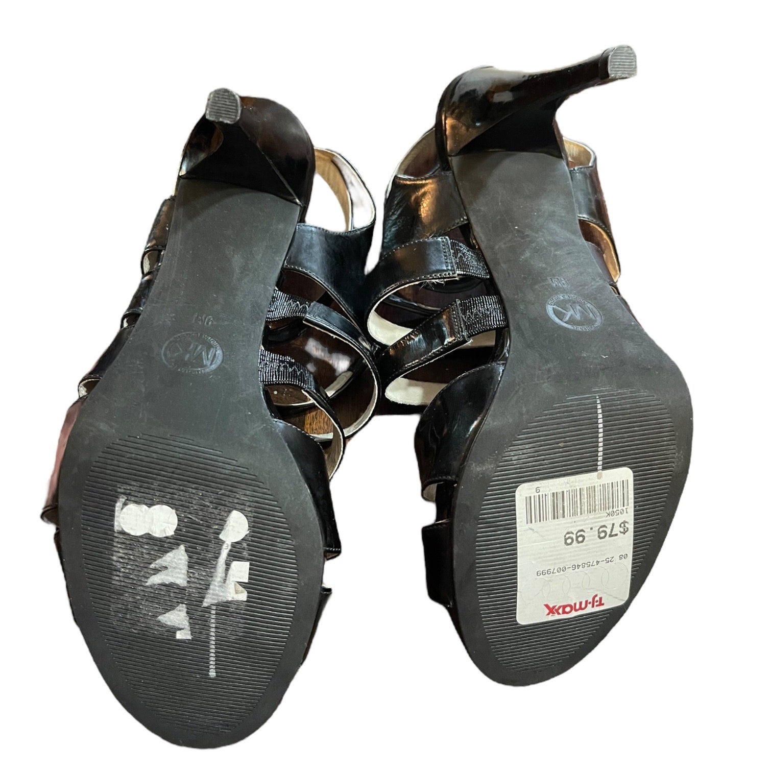 Black high-heeled shoes with visible brand labels on the soles against a white background