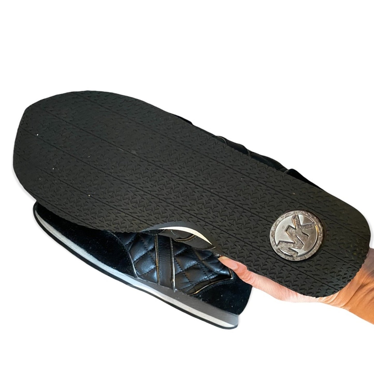 Black shoe insole with a brand logo held by a hand on a white background