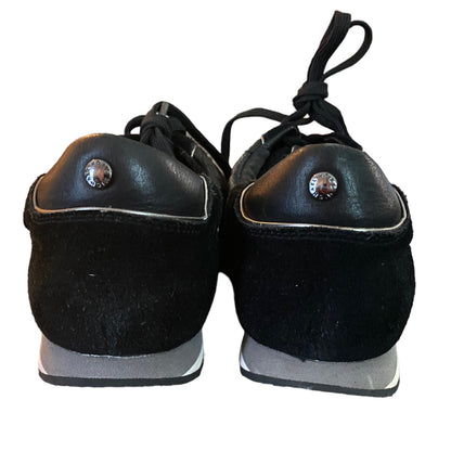 Pair of black shoes with silver buttons on a white background