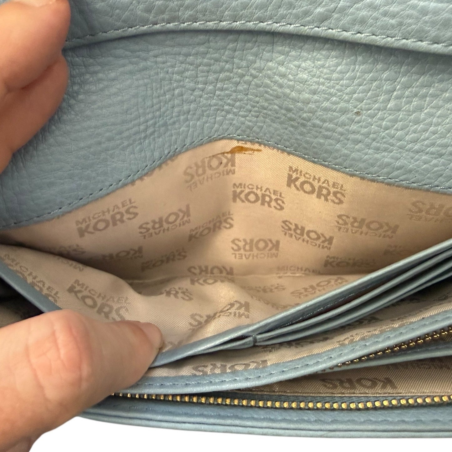 Light blue leather handbag with visible 'Michael Kors' logo on the interior lining.