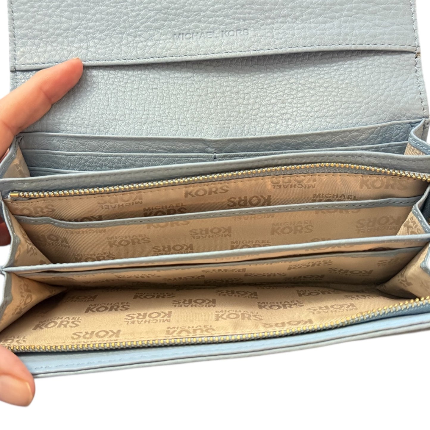 Light blue wallet with 'Michael Kors' branding, open to show card slots.