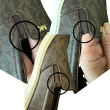 Close-up of a brown leather shoe with issues and visible stitching and MK logo, held by a hand.