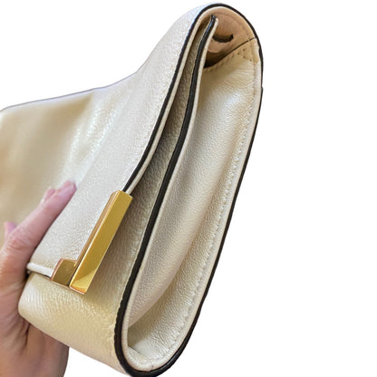 Side view of bag with a gold clasp held by a hand on a white background