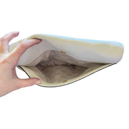 Hand holding open back pocket on purse against a white background