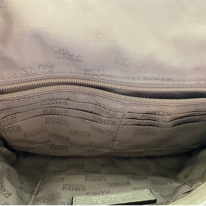 Close-up interior view of a Michael Kors handbag showing the branded interior lining with a repeating MICHAEL KORS pattern and a zippered compartment.