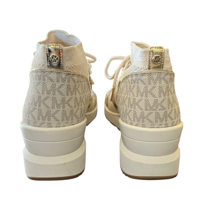 A pair of Michael Kors high-top sneakers shown from the back, featuring a beige and white monogram canvas upper, white laces, and chunky white platform soles with a gold-tone MK logo on the heel tab.