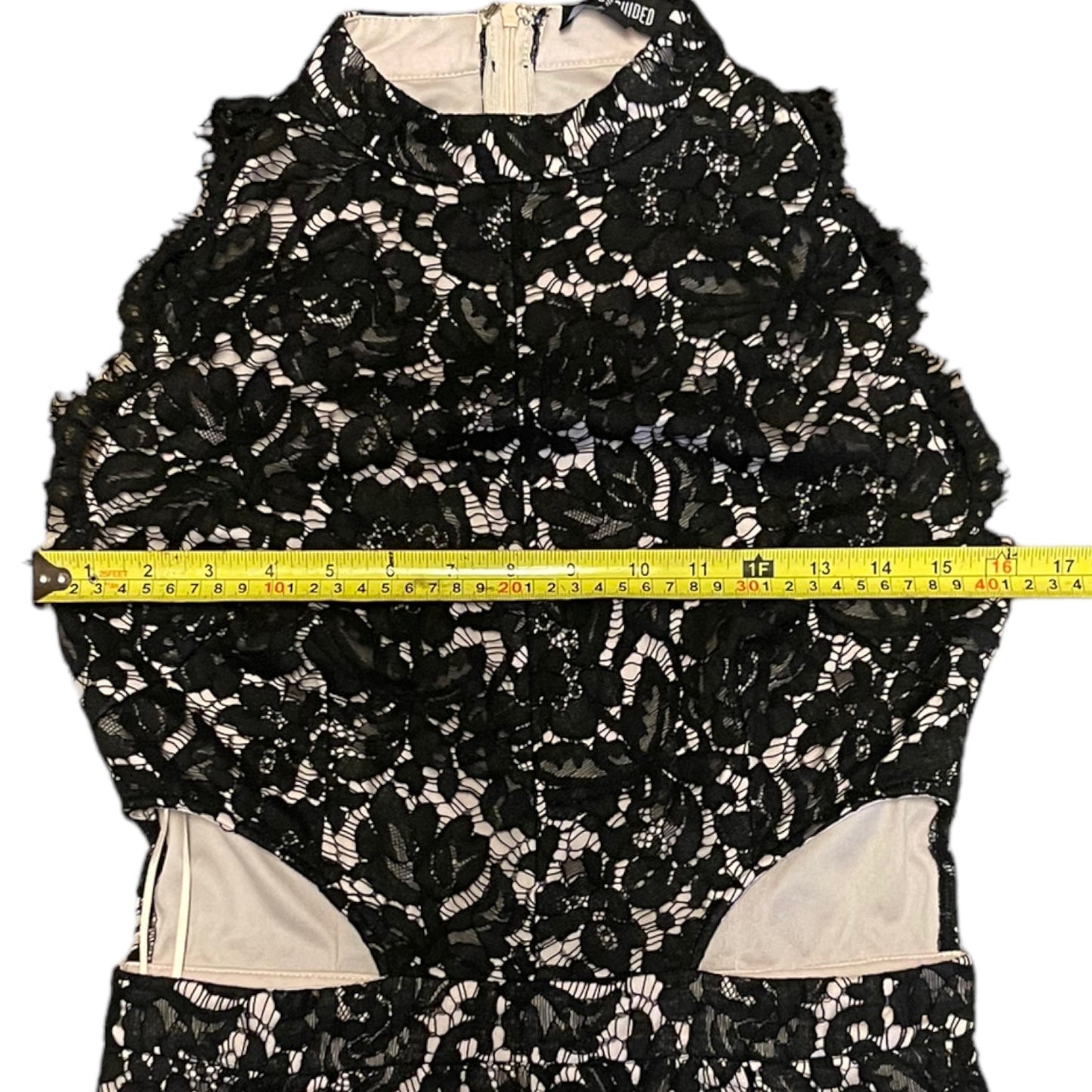 Black lace garment with a measuring tape across it on a white background