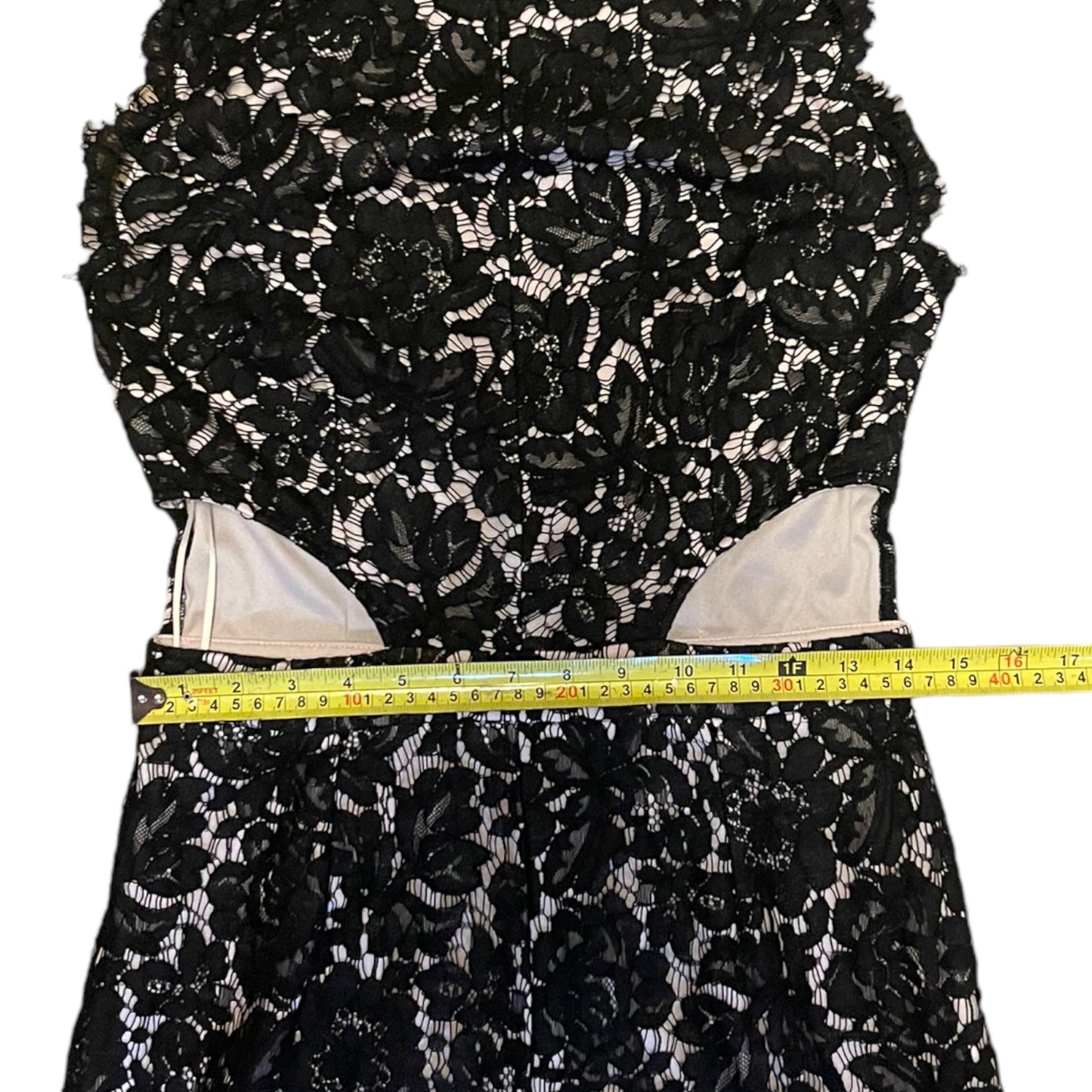 Black floral lace fabric with a measuring tape for scale on a white background