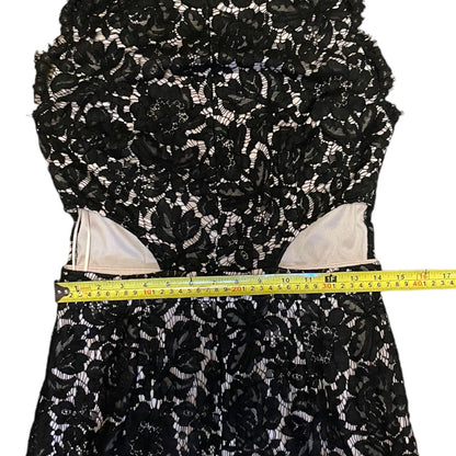 Black floral lace fabric with a measuring tape for scale on a white background