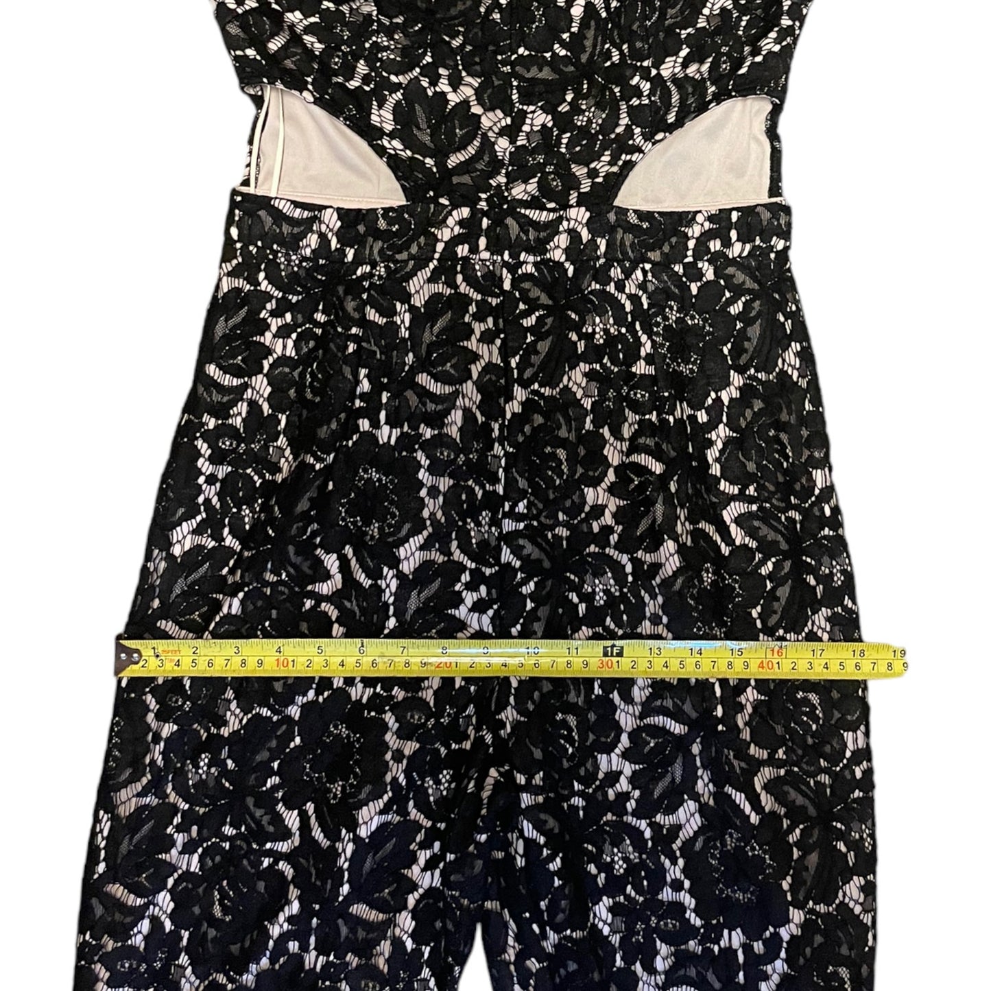 Black floral lace dress with a measuring tape on a white background