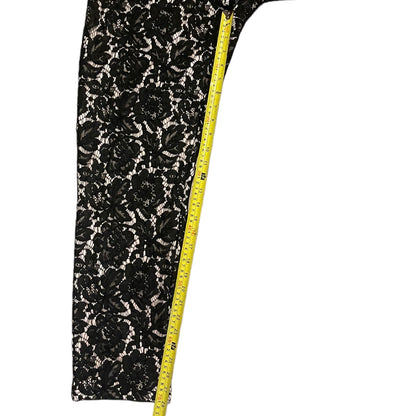 Black floral lace fabric with a measuring tape on a white background