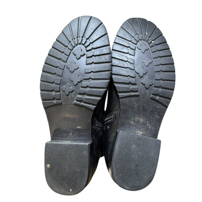 Black rubber shoes with tread pattern on a white background