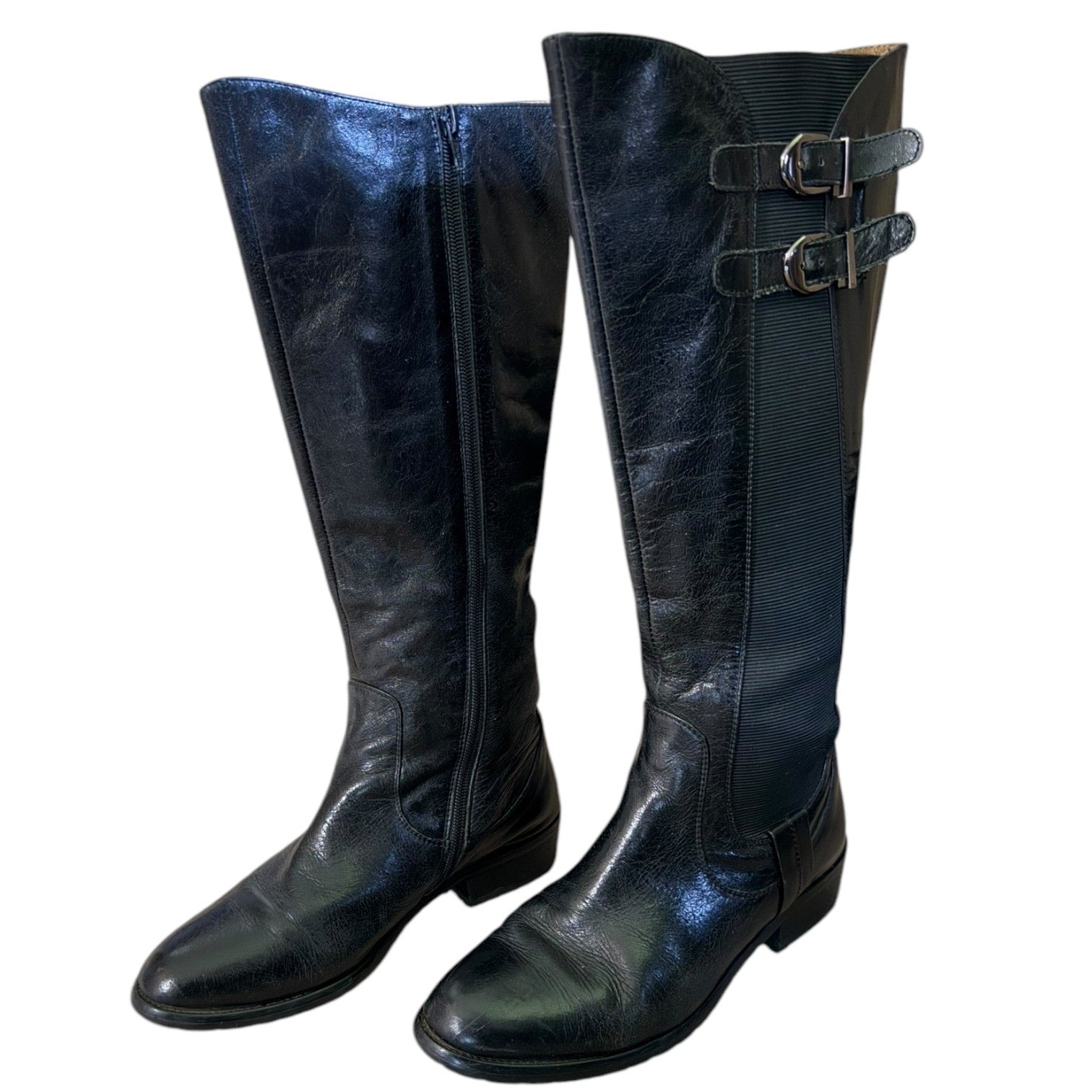 Front side of Pair of black knee-high boots with buckles on a white background