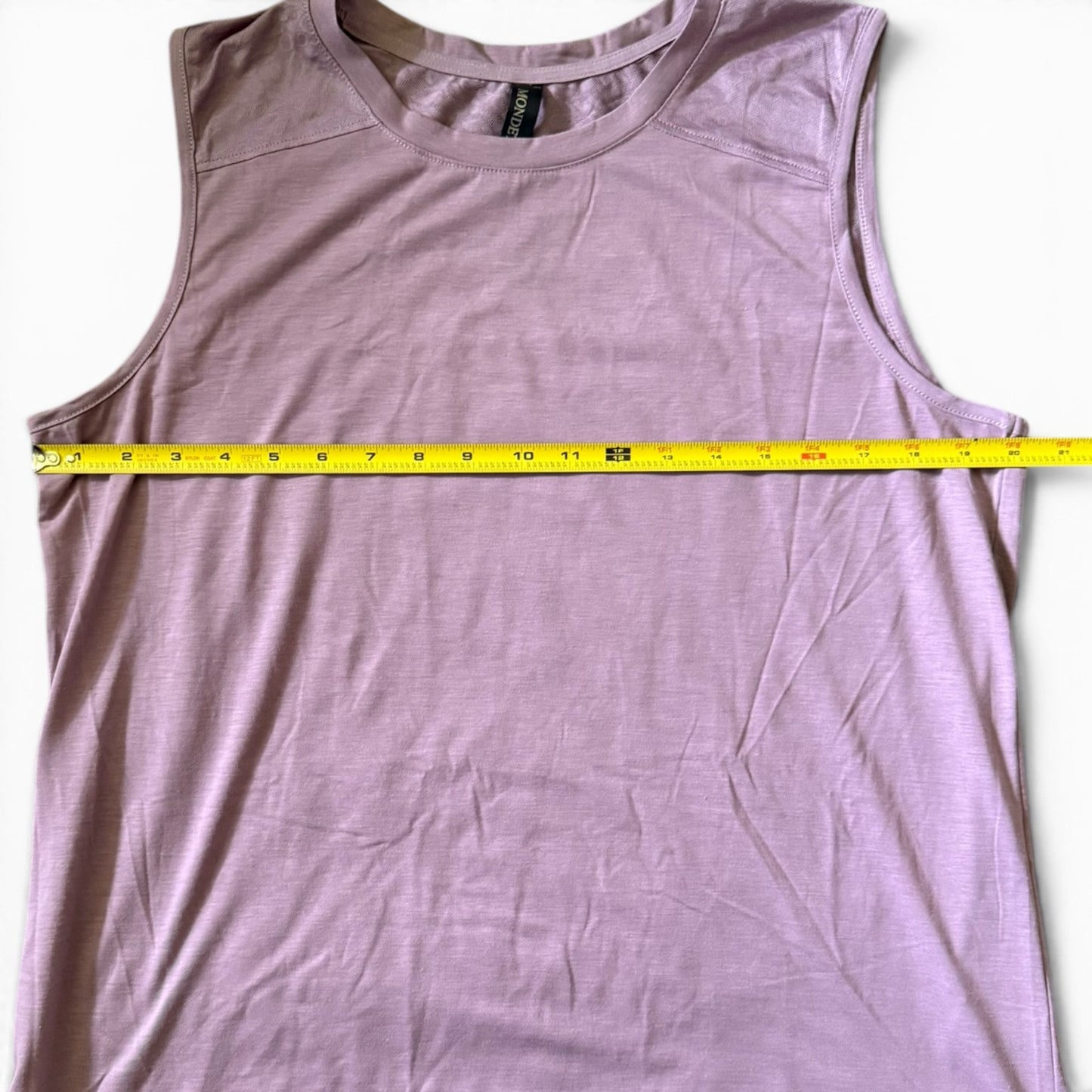 Purple shirt laying flat with a measuring tape laying across the top on a white background. 