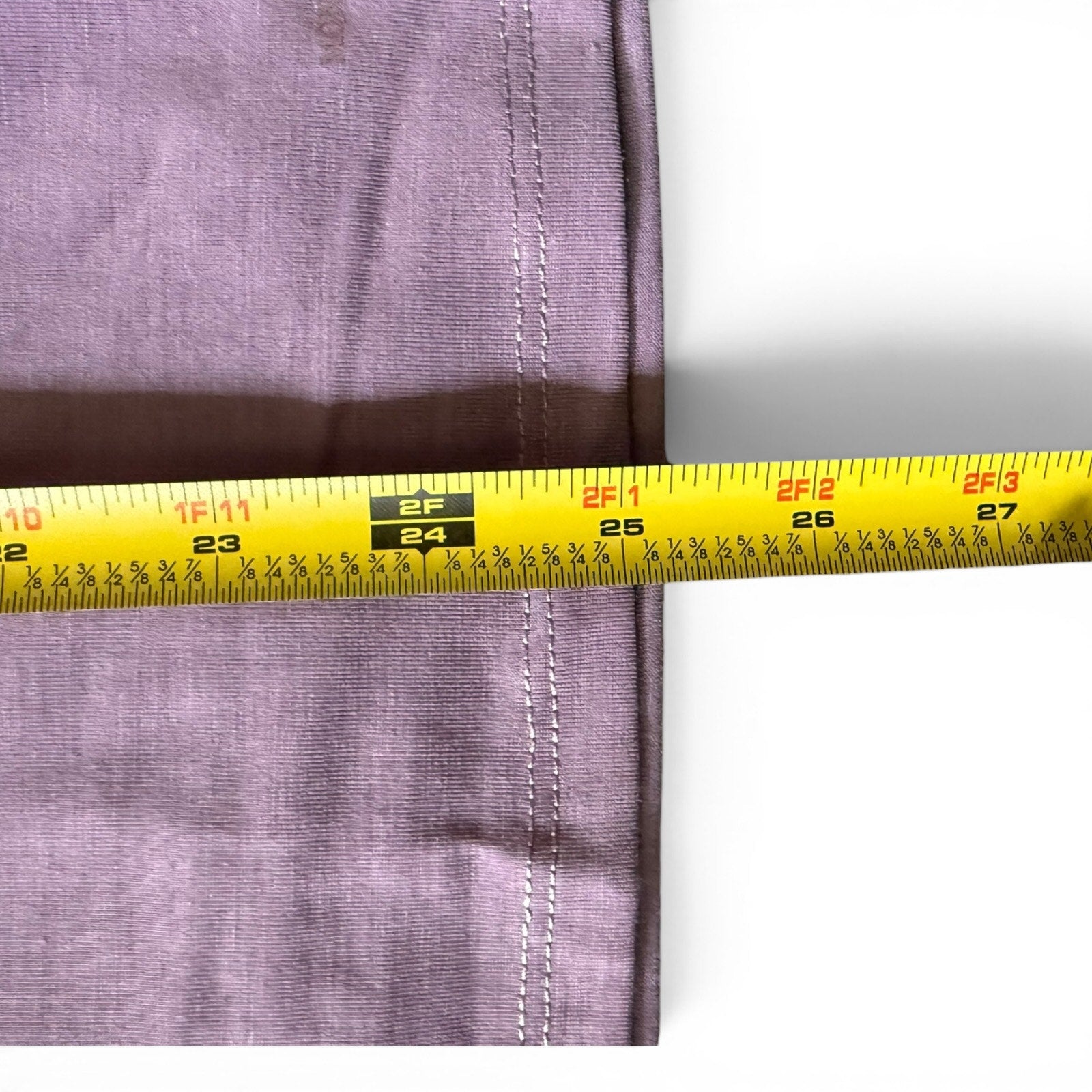 Purple shirt with a yellow measuring tape close up on a white background. 