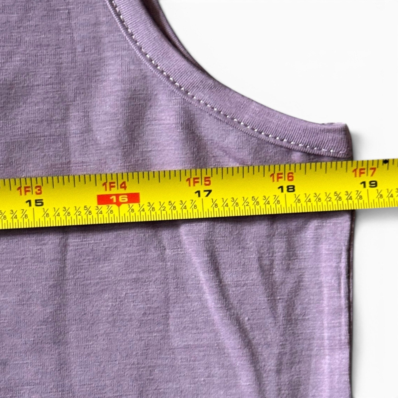 Close-up of a tank top with a yellow measuring tape across the chest to show the garment's width.