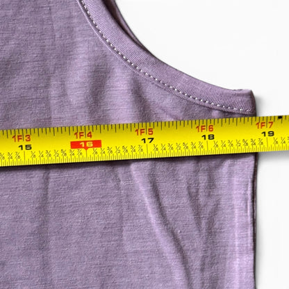 Close-up of a tank top with a yellow measuring tape across the chest to show the garment's width.