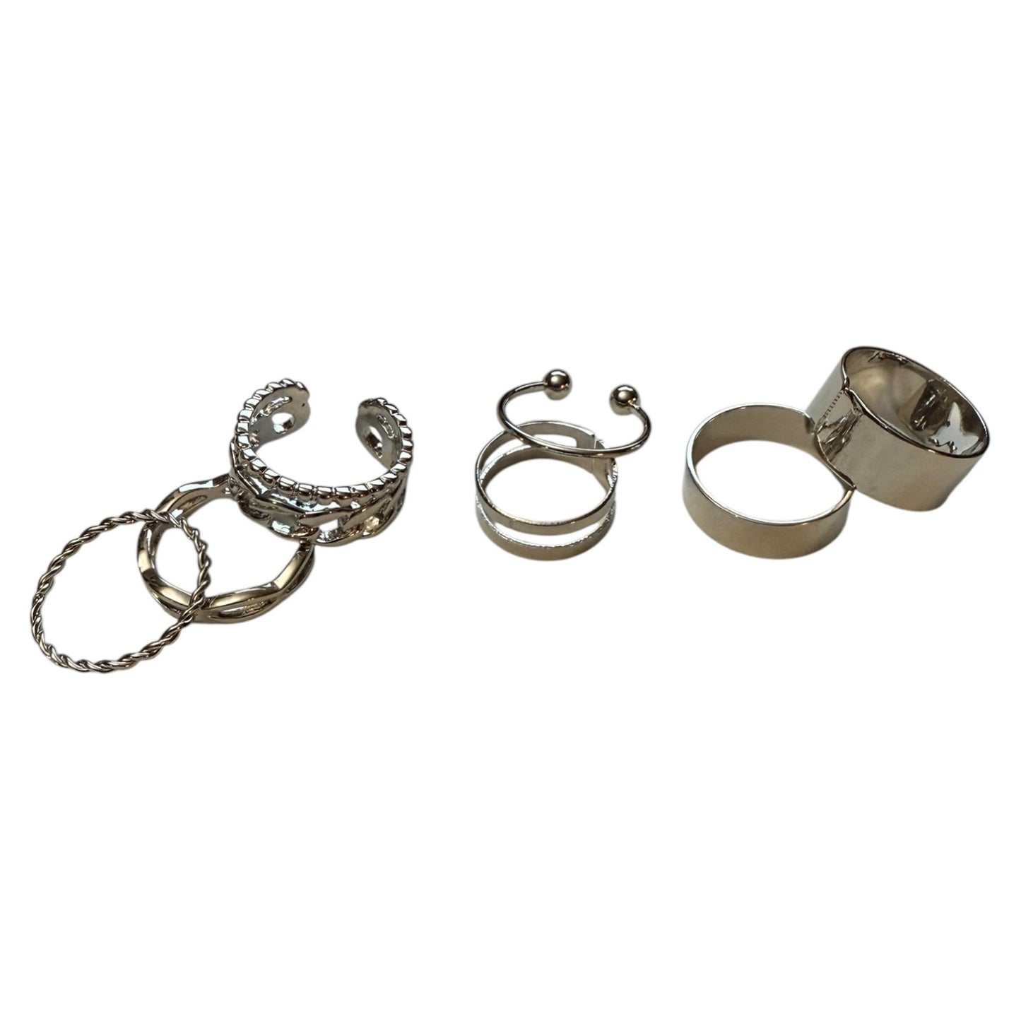 Seven silver-toned metal rings and cuffs displayed separately on a plain white background.
