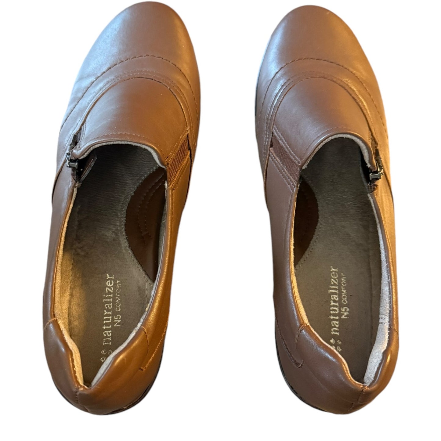 Top of Pair of brown shoes with a visible brand name on a white background