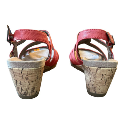 Pair of orange sandals with cork sole on a white background