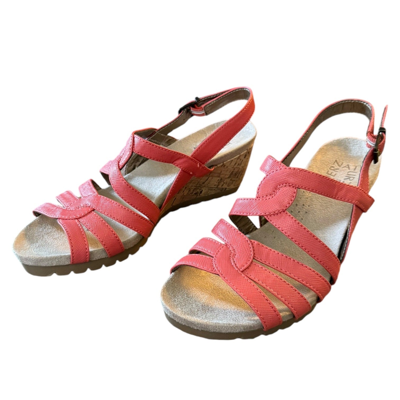 Pair of orange sandals with a wooden wedge sole on a white background