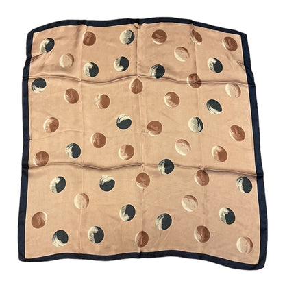 A square scarf laid flat on a white background, featuring a pink base with a pattern of large polka dots, finished with a solid blue border.
