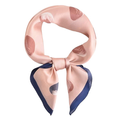 A scarf with a light pink base, abstract brown and gray spots, and a navy blue border, styled in a knot on a solid white background.