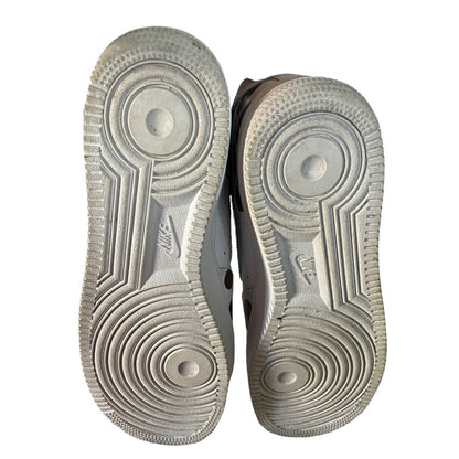 The soles of a pair of Nike sneakers, showing the textured circular tread patterns and embossed Nike logos against a white background.