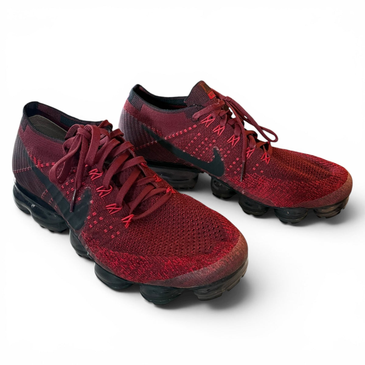 A pair of Nike Air VaporMax Flyknit sneakers in a deep burgundy red and black colorway, displayed on a clean white background.