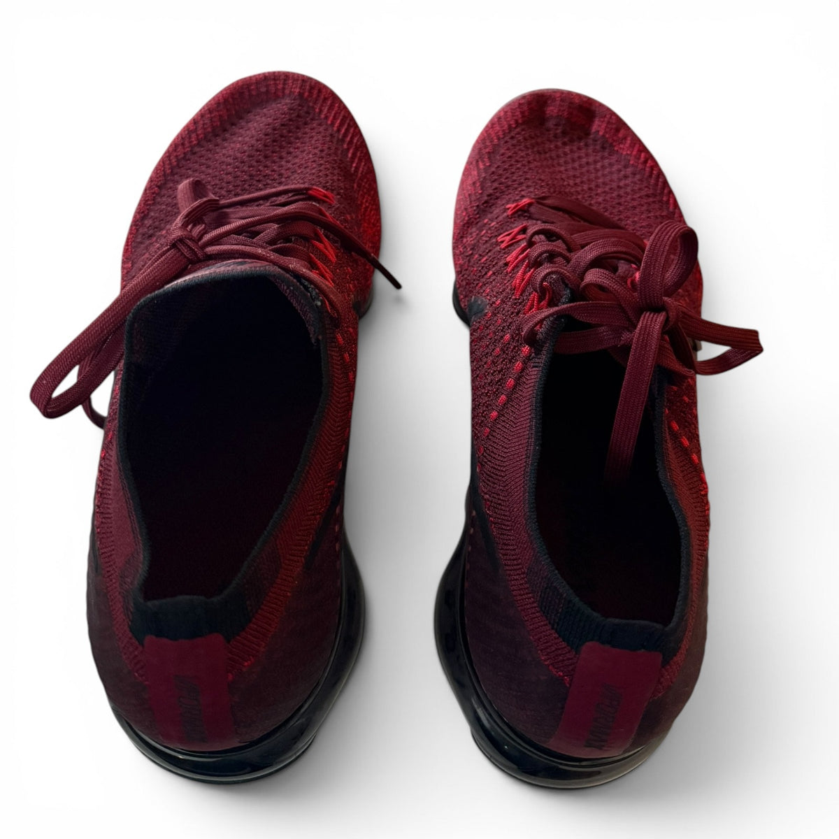 A pair of dark red knit athletic sneakers shown from a top-down view on a white background.