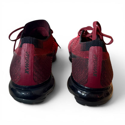 A pair of red and black Nike Air VaporMax running shoes shown from the back, featuring a textured knit upper, burgundy heel tabs with black branding, and black air cushioned soles.