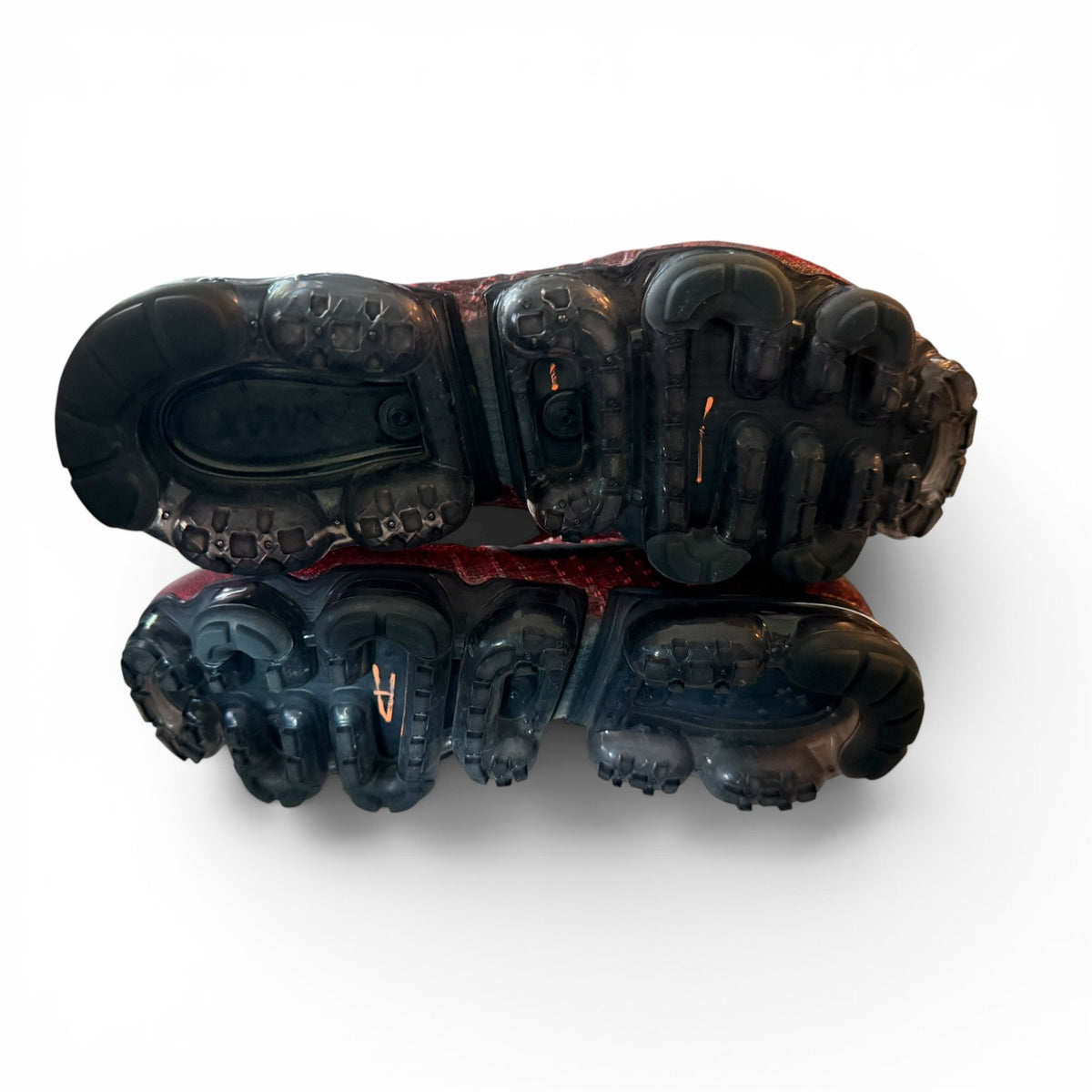 A pair of black athletic shoes shown from a top-down perspective, highlighting their rugged, multi-angled rubber soles, set against a plain white background.
