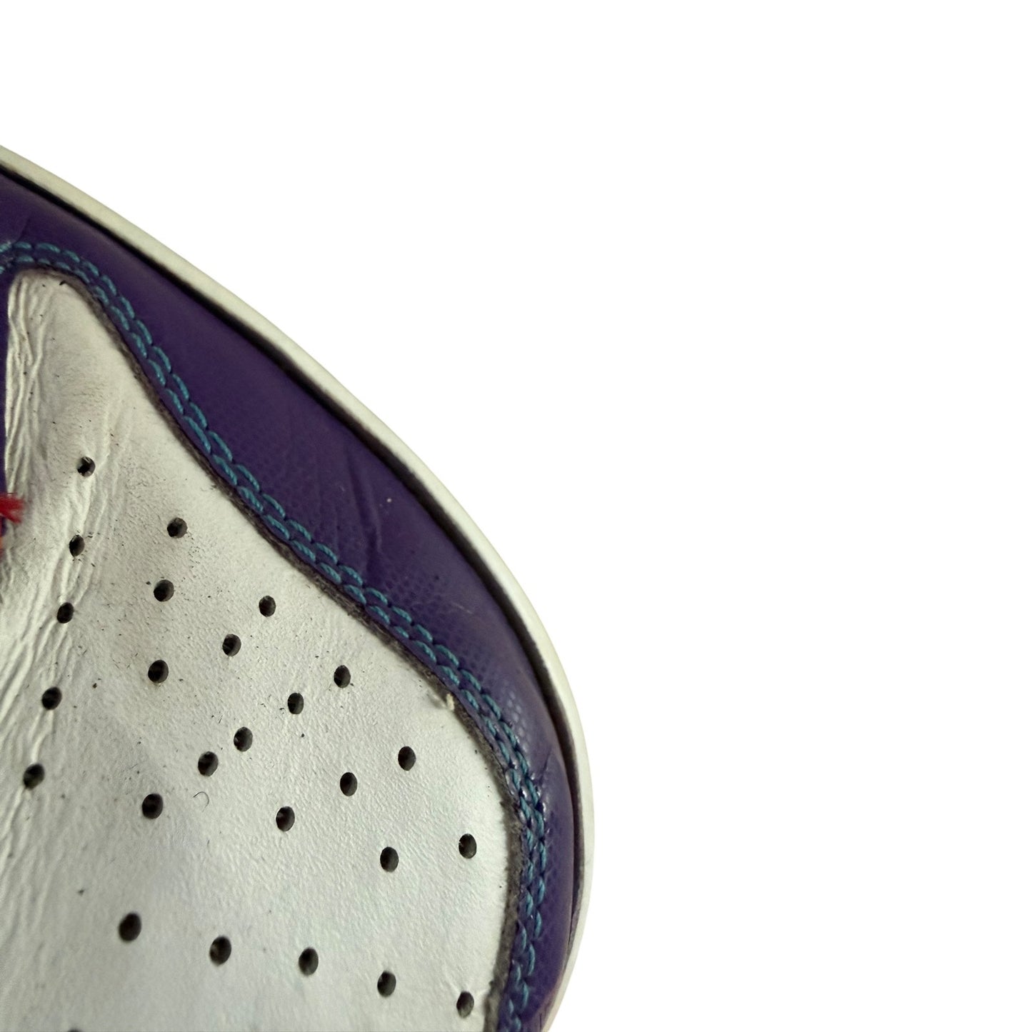 Close-up of a shoe's sole with perforations and blue stitching on a white background