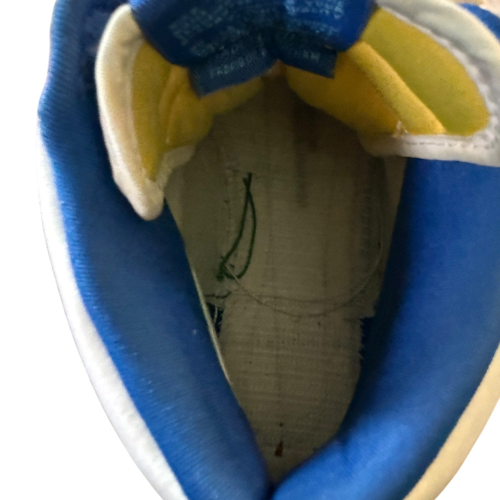 Close-up interior of a blue and yellow shoe with a brand label on a white background