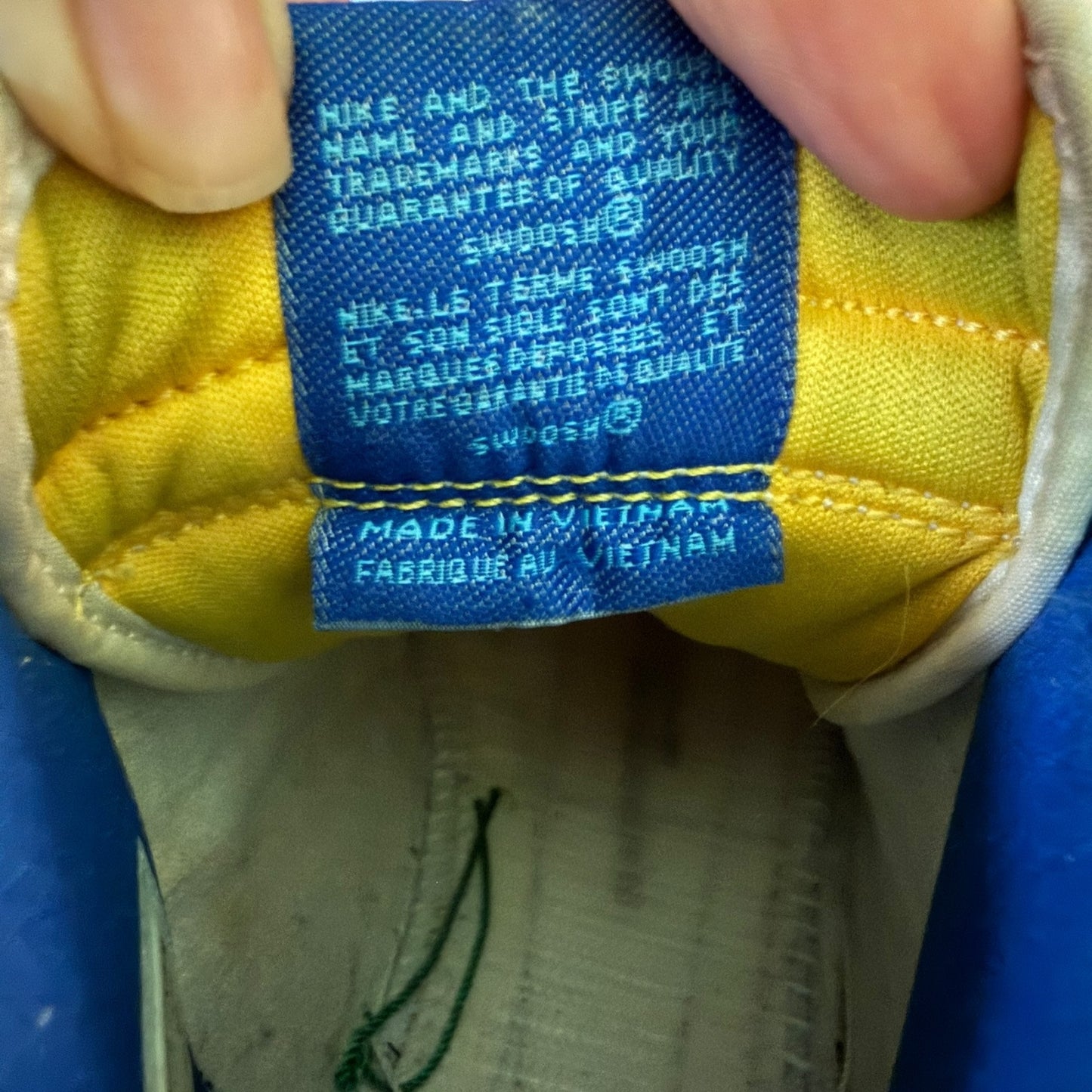 Close-up of a Nike shoe label with text and 'Made in Vietnam' on a yellow and blue background.