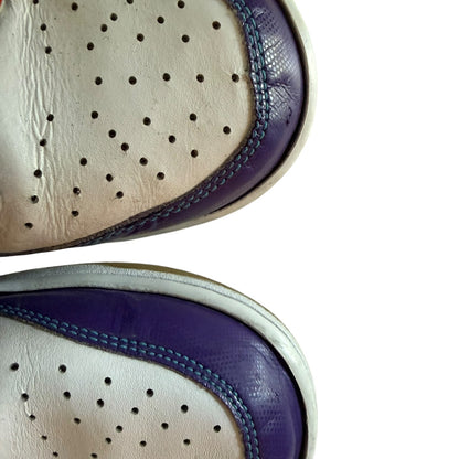 Close-up of a white shoe with purple sole and blue stitching on a white background