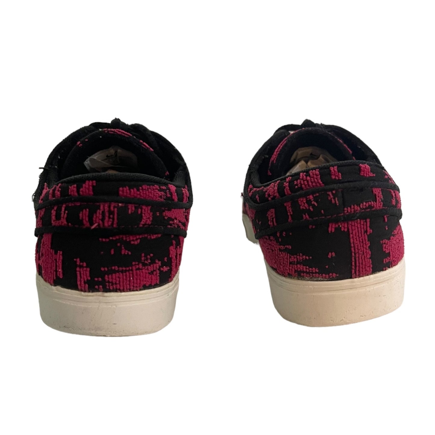A pair of low-top canvas sneakers shown from the back, featuring a black and vibrant pink abstract pattern on the uppers and white rubber soles.