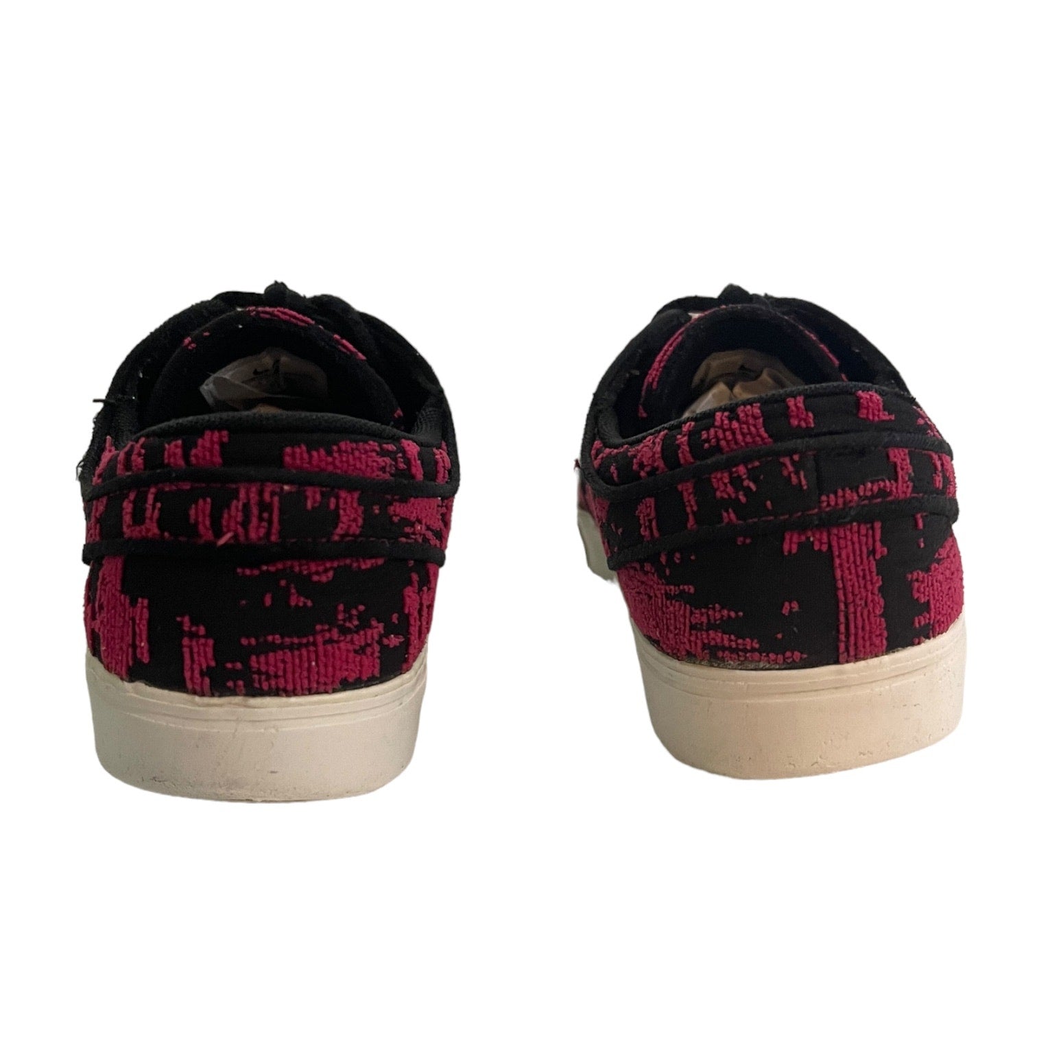 A pair of low-top canvas sneakers shown from the back, featuring a black and vibrant pink abstract pattern on the uppers and white rubber soles.