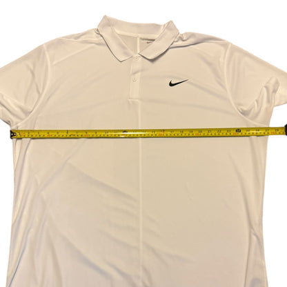 A white Nike polo shirt laid flat on a white background, with a yellow tape measure stretched horizontally across the chest to show the width.