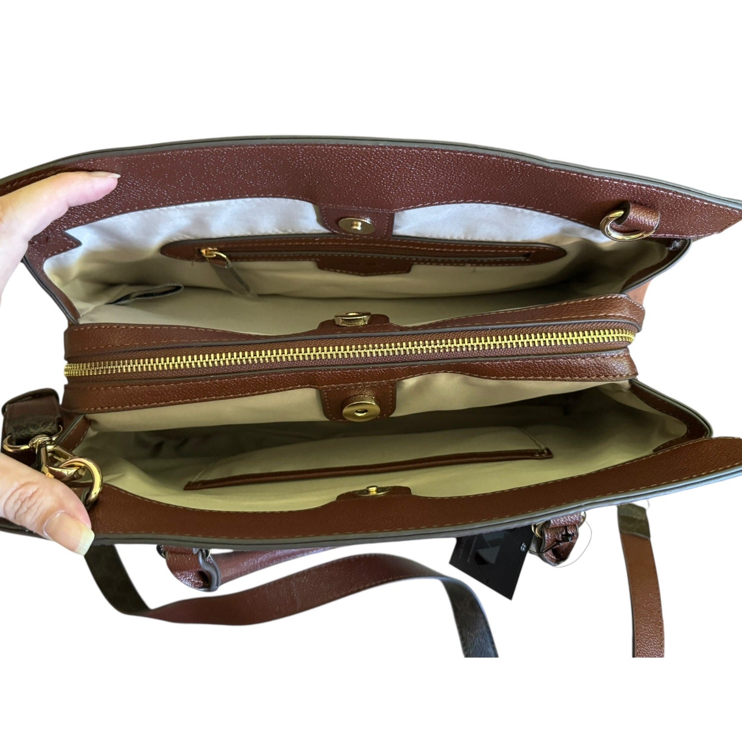 Brown leather handbag interior with gold zippers and hardware on a white background