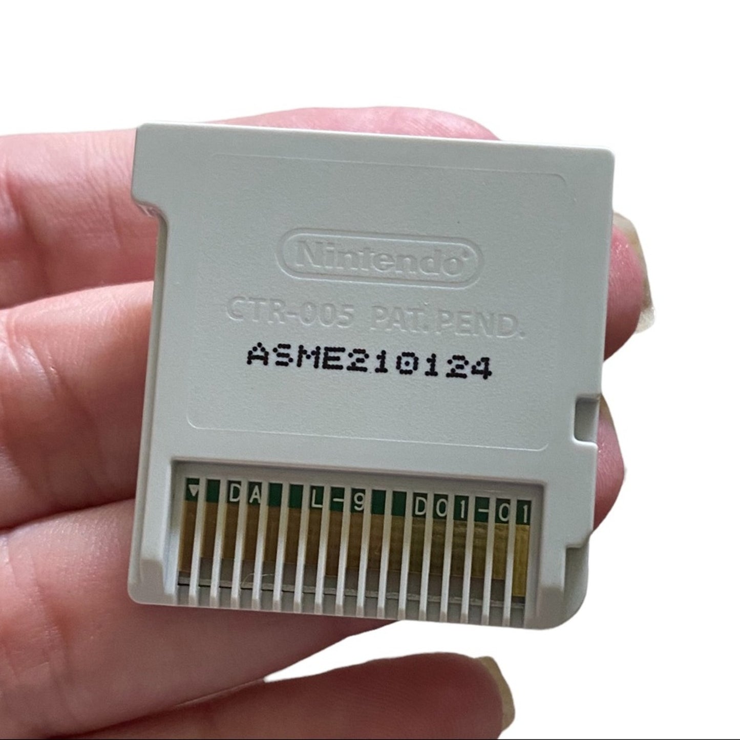 Nintendo game cartridge held in a hand with a white background