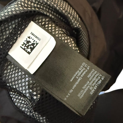 Close-up of a garment's interior label area showing a dark fabric brand tag and a white size/QR code label attached to black mesh lining.