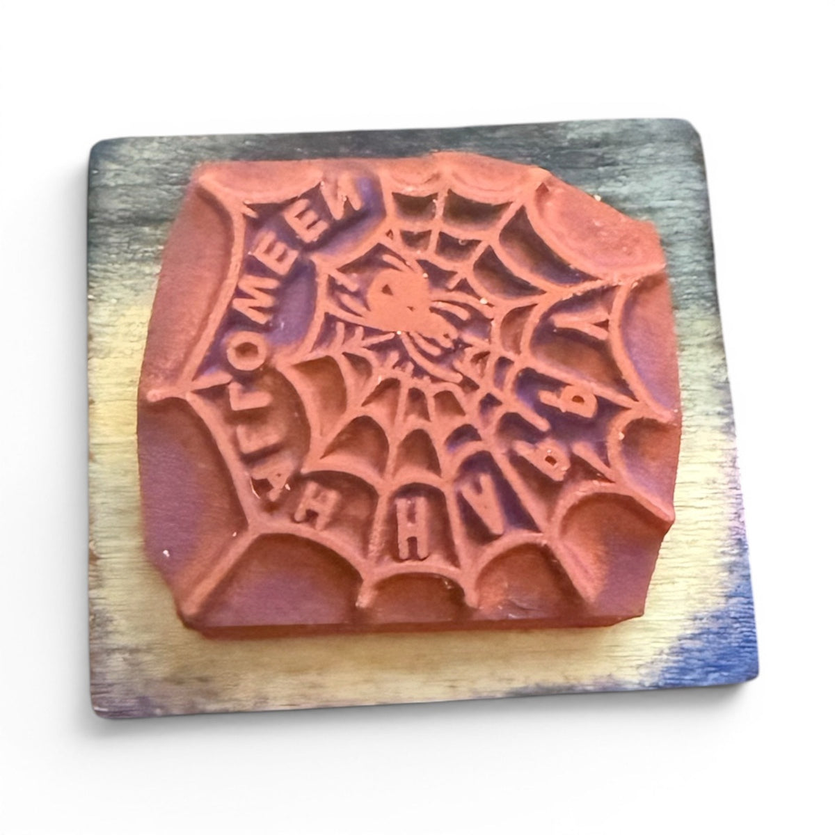 Wooden stamp with spider web design and 'Happy Halloween' text on a wooden block.